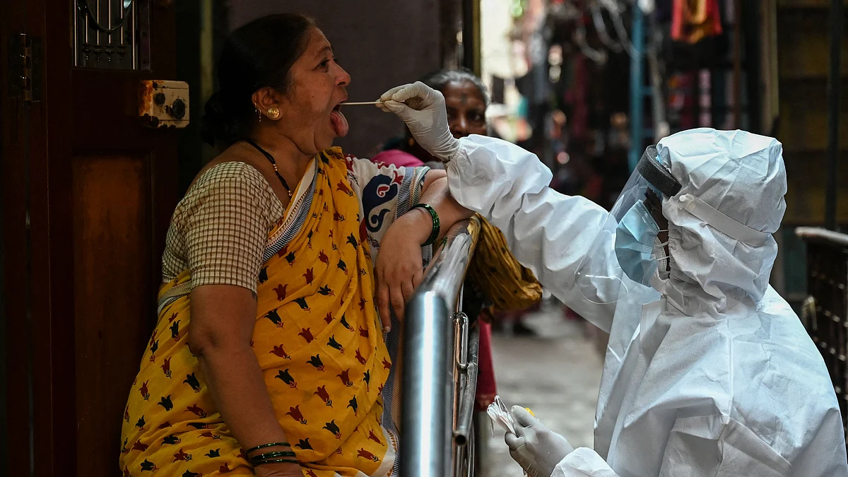 A health worker takes a swab sample of a resident for a COVID-19 test at Dharavi slum in Mumbai