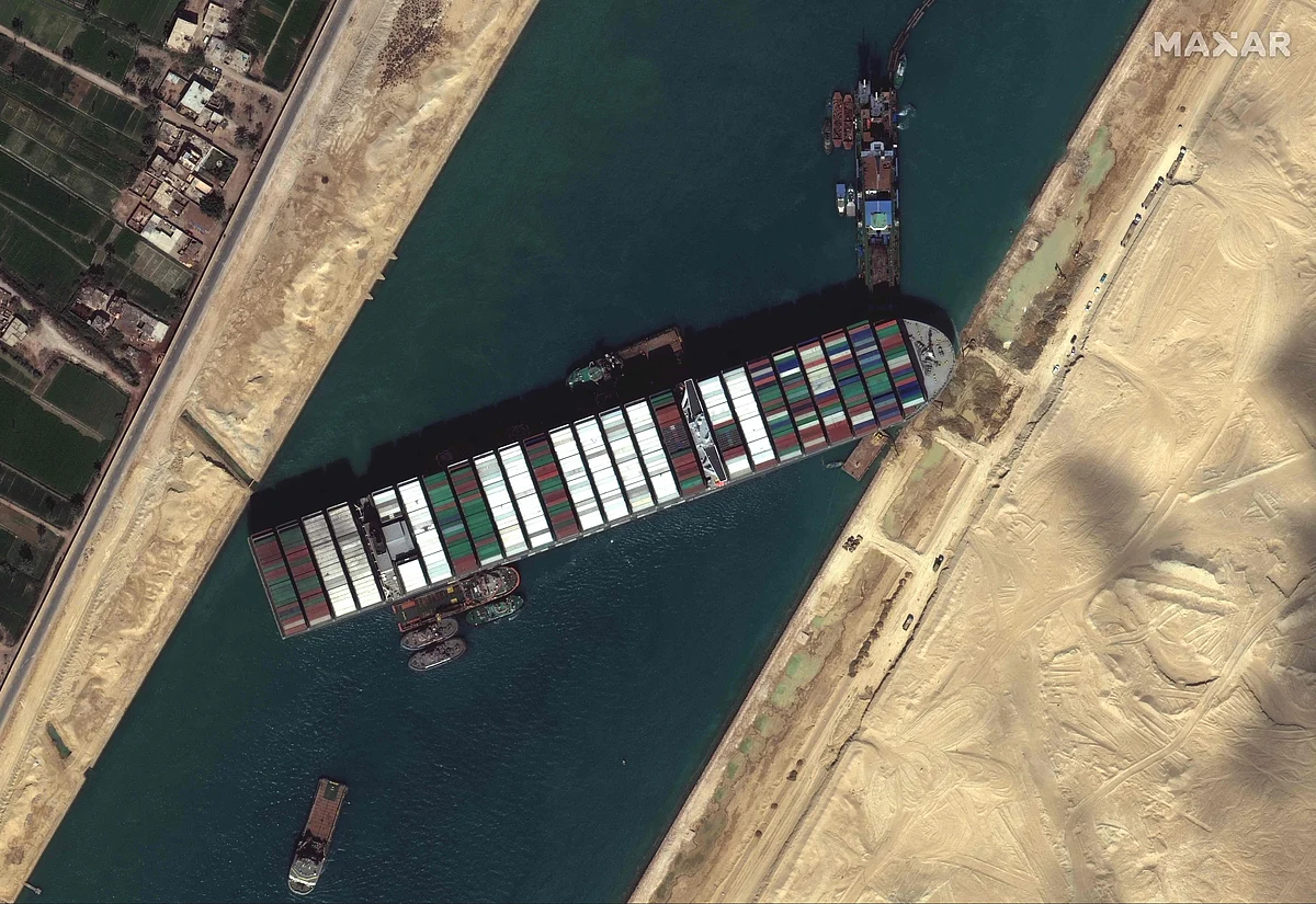 This satellite imagery released by Maxar Technologies shows tug boats and dredgers on March 27, 2021, attempting to free the Taiwan-owned MV Ever Given lodged sideways and impeding all traffic across Egypt's Suez Canal. - The container ship, which is longer than four football fields, has been wedged diagonally across the entire canal since March 23,