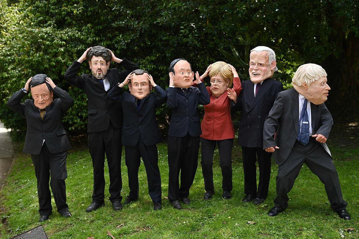 Extinction Rebellion environmental activists wear headgear depicting the G7 leaders as they demonstrate in a park in Falmouth, Cornwall during the G7 summit on June 12, 2021.