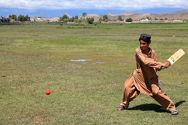Young Afghan boy gearing up slog the ball for a six