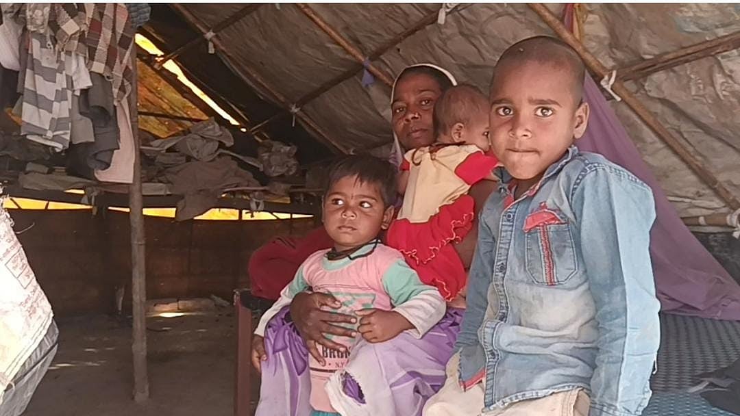A family in the village of Bichpuri sitting under a tarpaulin shelter after their house was demolished