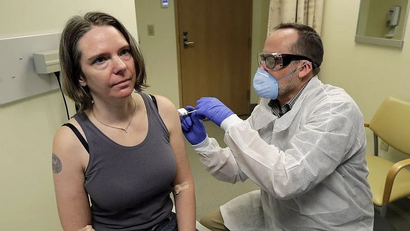 A pharmacist gives a volunteer the first shot in the first-stage safety study clinical trial of a potential vaccine for COVID-19.