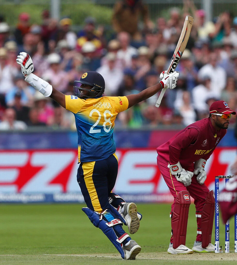 Sri Lanka's batsman Avishka Fernando raises his bat and helmet to celebrate scoring a century.