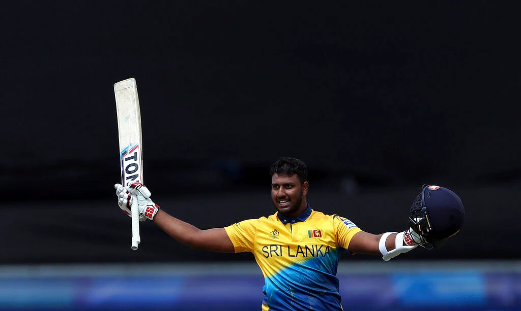 Sri Lanka's batsman Avishka Fernando raises his bat and helmet to celebrate scoring a century.