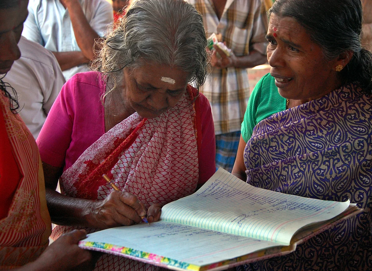பதிவேட்டில் ஆர்வமுடன் கையெழுத்திடும் மூதாட்டி.
