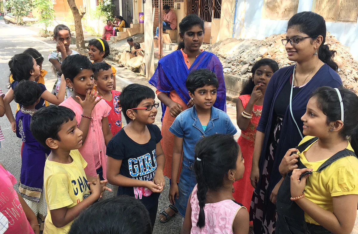 வீதியின் நடுவில் நின்று கதை சொல்லி விளையாடும் சிறுமிகள்