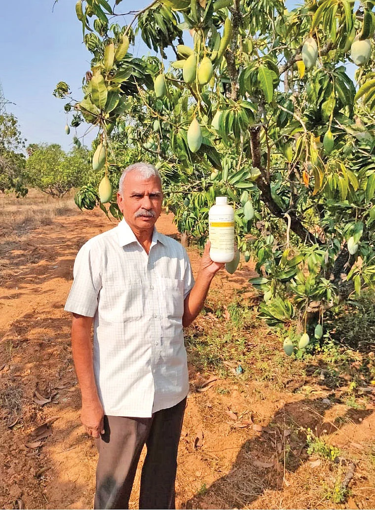 தனது தோட்டத்தில் நானோ திரவ பாட்டிலுடன் சாந்தகுமார்