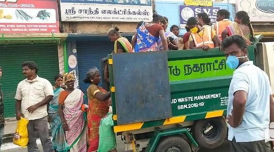 குப்பை வண்டியில் செல்லும் தூய்மைப் பணியாளர்கள்