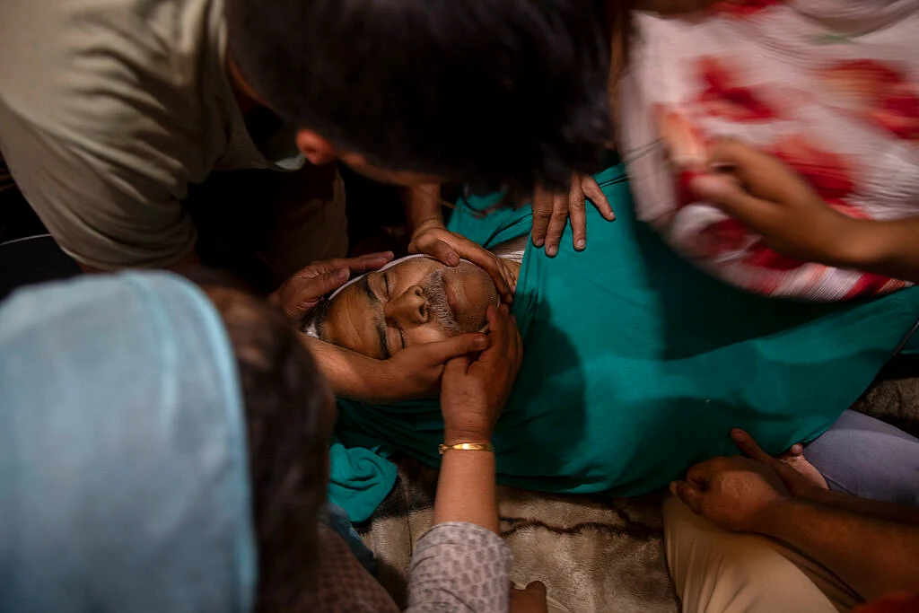 Relatives grieve near the body of civilian Bashir Ahmed Khan, inside his residence on the outskirts of Srinagar