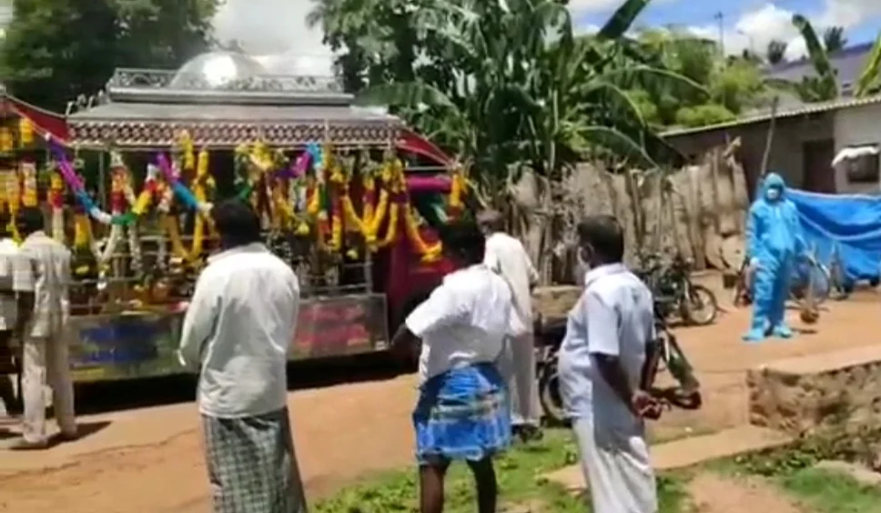 கவச உடை அணிந்து இறுதிச் சடங்கு செய்யும் மகன்