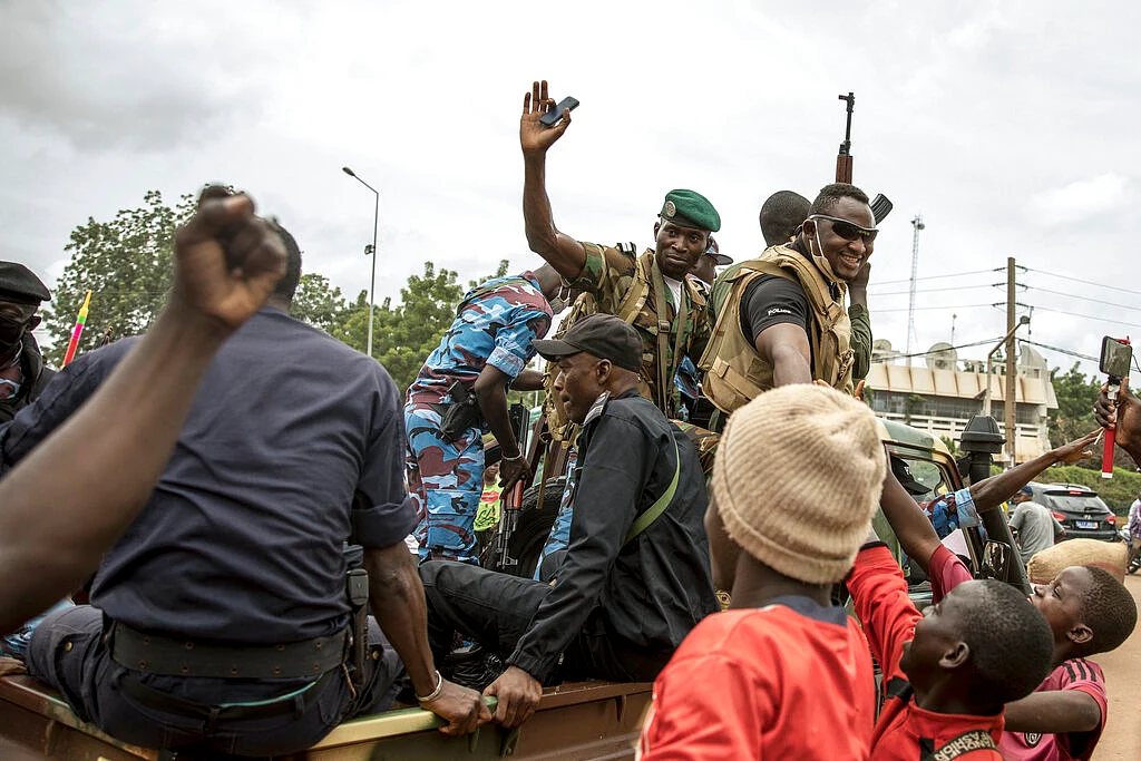 People cheer in celebration as security forces drive through the streets of the capital Bamako, Mali, Wednesday, Aug. 19, 2020