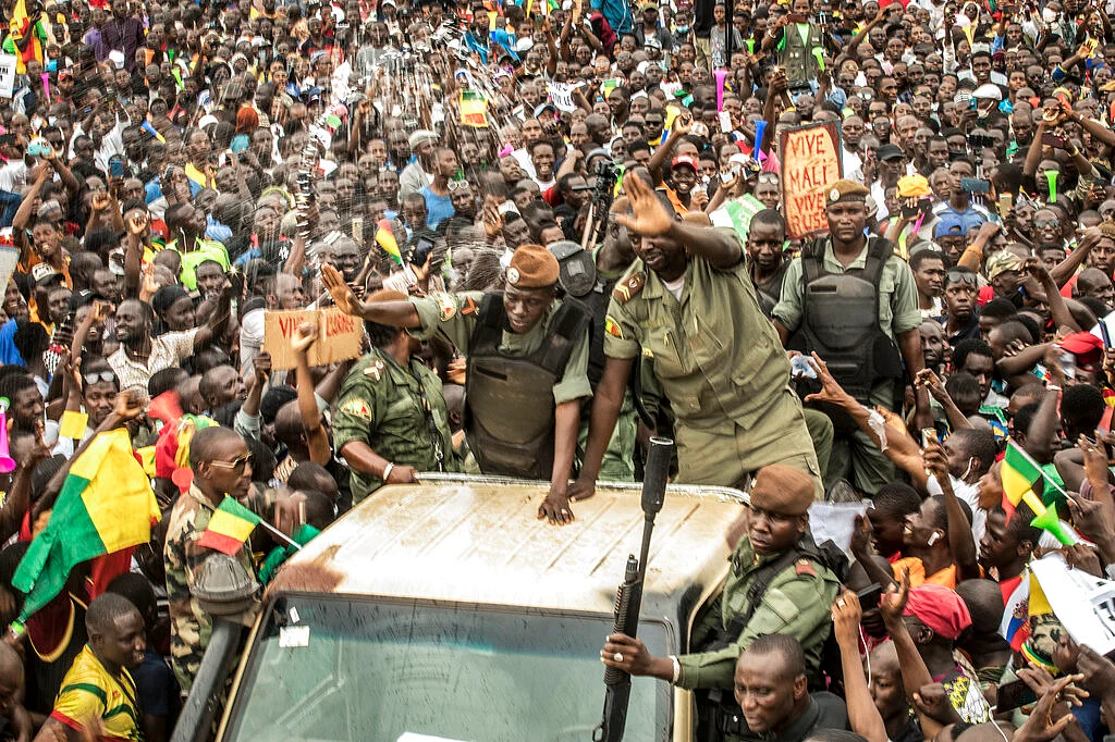 An unidentified representative of the junta waves from a military vehicle as Malians supporting the recent overthrow of President Ibrahim Boubacar Keita gather to celebrate in the capital Bamako, Mali Friday, Aug. 21, 2020.