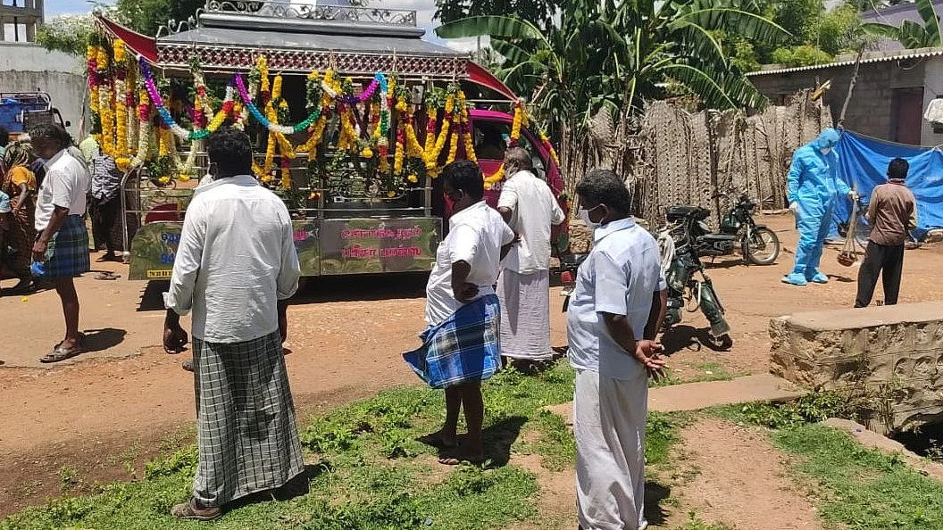 கவச உடை அணிந்து இறுதிச் சடங்கு செய்யும் மகன்