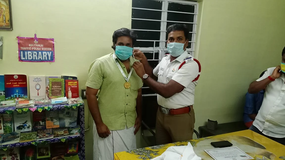 இளைஞருக்கு பதக்கம் அணிவிக்கும் கார்த்திகேயன்