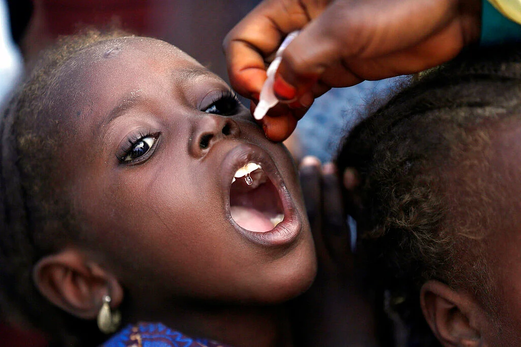 In this Sunday, Aug. 28, 2016 file photo, a health official administers a polio vaccine to a child at a camp for people displaced by Islamist Extremists, in Maiduguri, Nigeria. Health authorities on Tuesday, Aug. 25, 2020 are expected to declare the African continent free of the wild poliovirus after decades of effort, though cases of vaccine-derived polio are still sparking outbreaks of the paralyzing disease in more than a dozen countries.