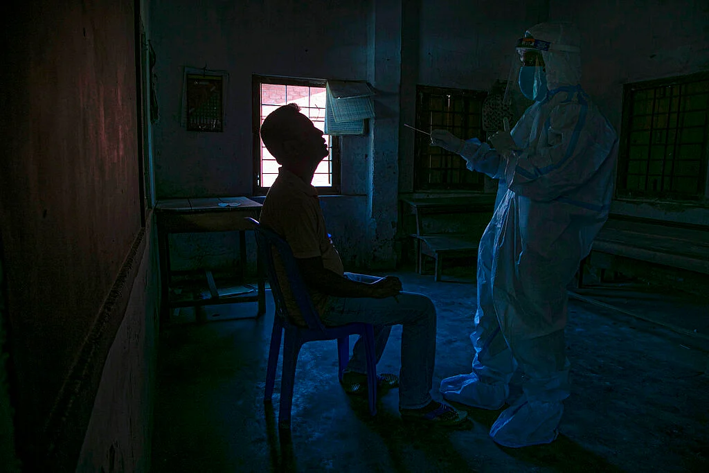 A health worker takes a nasal swab sample to test for COVID-19 in Gauhati