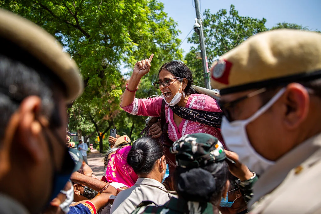 An Indian activist shouts slogans as she is detained by police during a protest in New Delhi, India