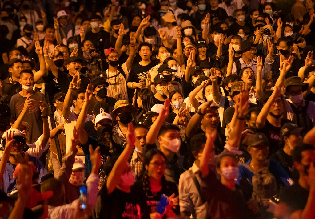 Pro-democracy protesters raise a three-finger salute, a sign of resistance, as they gather outside the Government House during a rally in Bangkok, Thailand