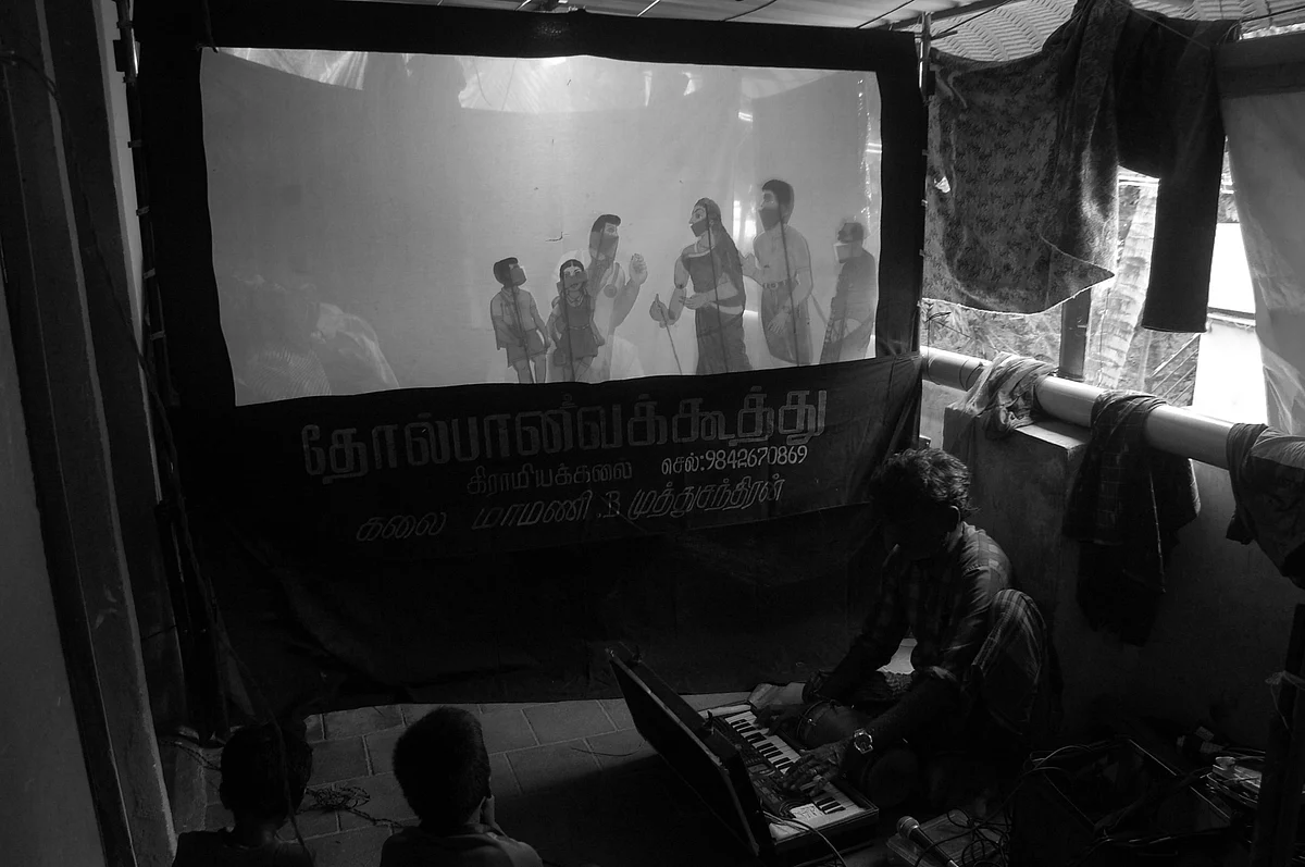 வீட்டின் சூழலில் இசை இசைத்து தோல்பாவை கூத்து நடத்தும் கலைஞர்