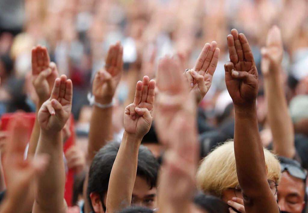 Pro-democracy protesters raise three-finger salutes, a symbol of resistance, as they gather at a junction in Bangkok, Thailand
