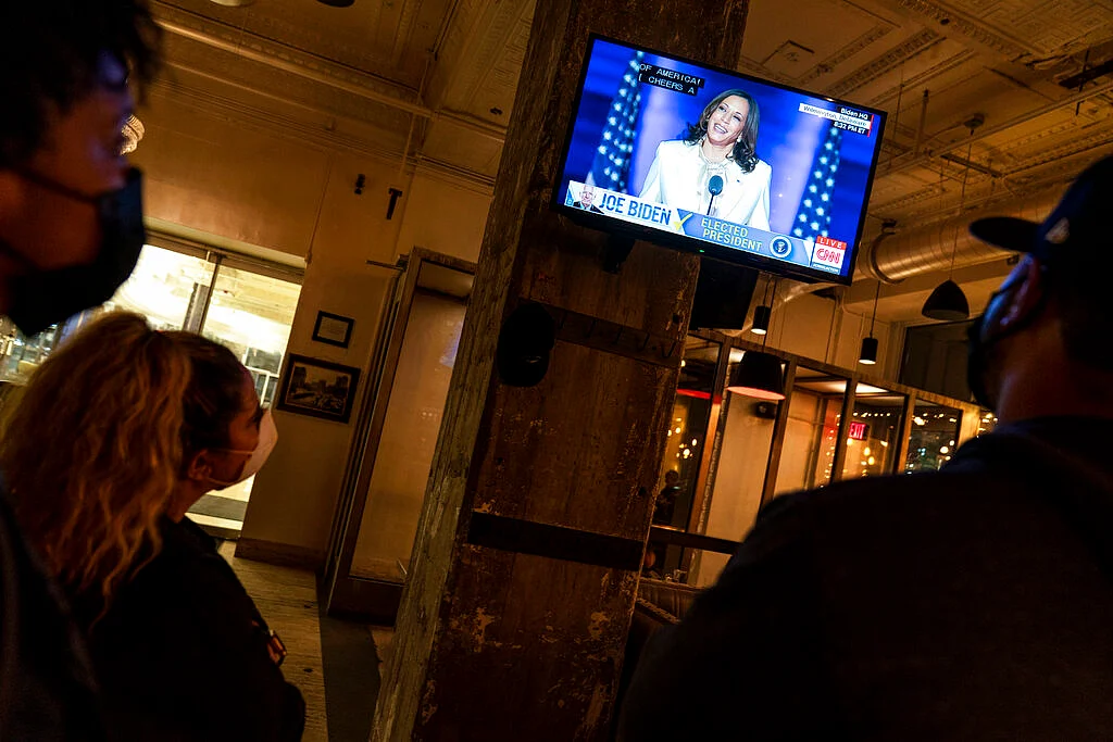 A broadcast of Vice President-elect Kamala Harris speaking is shown on a television