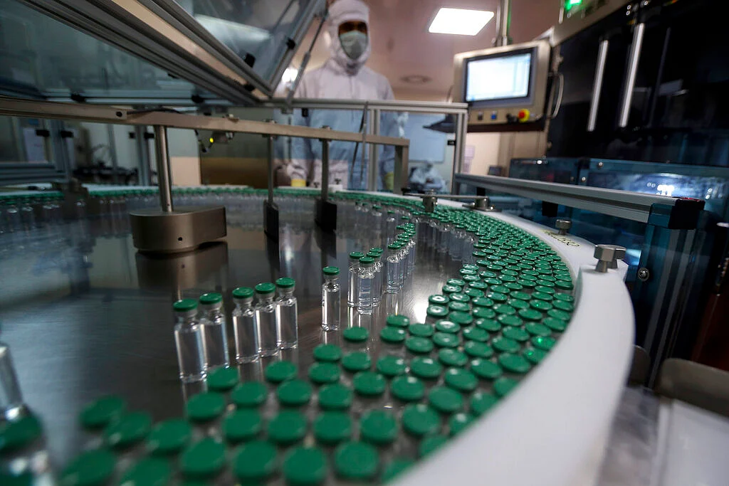 An employee operates a filling machine of COVID-19 vaccine at the Serum Institute of India, Pune, India