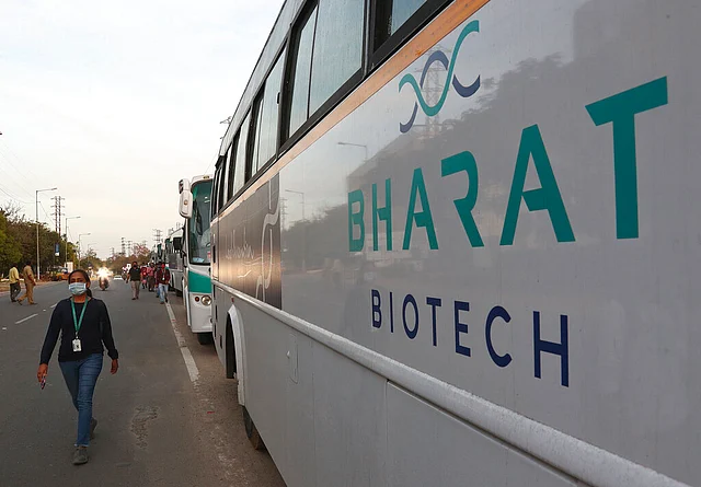 An employee of Bharat Biotech walks to board a bus parked outside the office on the outskirts of Hyderabad, India