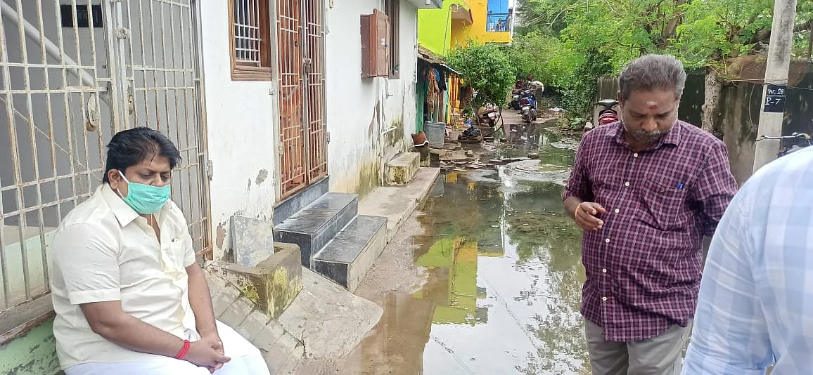 கழிவ நீரை அகற்ற கோரி அமர்ந்திருக்கும் மணிகண்டன்