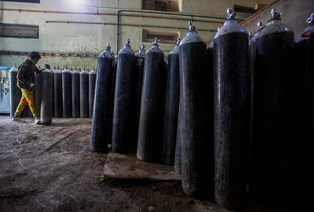 A Kashmiri worker moves an oxygen cylinder as they stock them inside a hospital in Srinagar