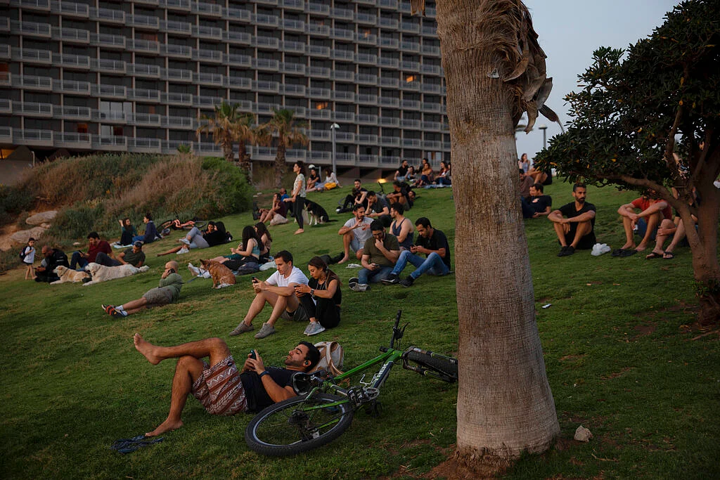 People without face masks watch the sunset, in Tel Aviv, Israel, Sunday, April 18, 2021. mass vaccination drive.