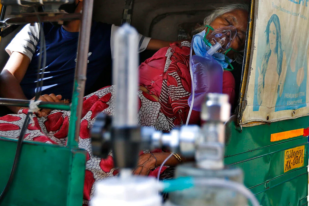 A COVID-19 patient wearing oxygen mask waits inside an auto rickshaw to be attended and admitted to a dedicated COVID-19 government hospital in Ahmedabad, India