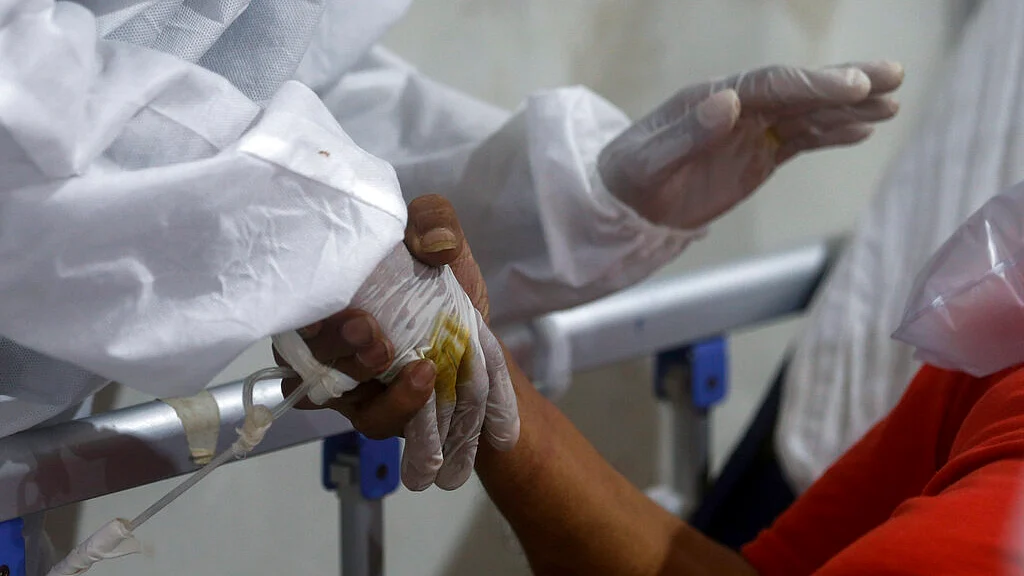 A nurse holds the hand of a patient