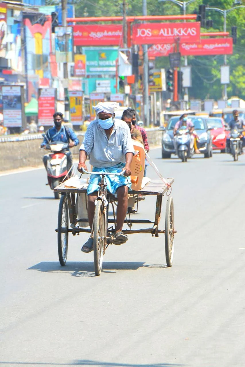 சுட்டெரிக்கும் வெயிலில் சைக்கிள் ரிக்ஷா ஓட்டிச் செல்லும் தொழிலாளி