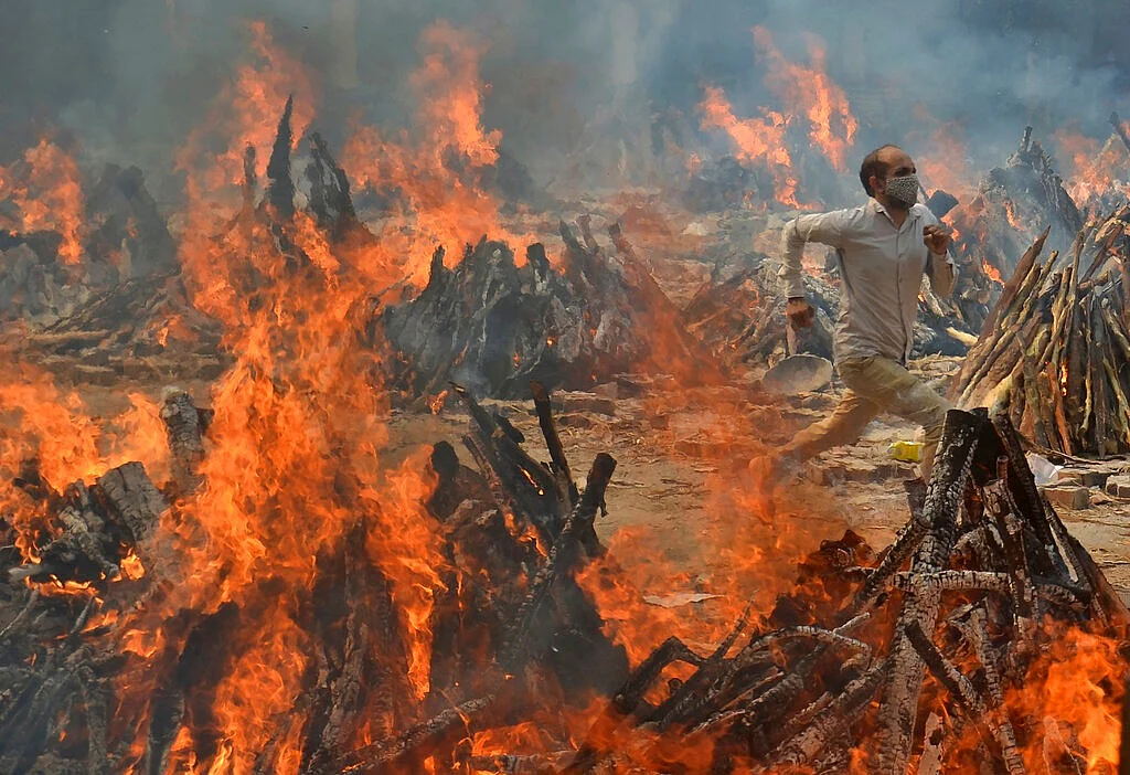 A man runs to escape heat emitting from the multiple funeral pyres