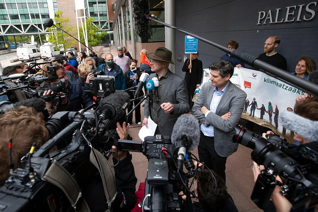 Friends of Earth director Donald Pols, center with hat, and lawyer Roger Cox, right, talk to the press after the verdict in the court case of Milieudefensie, the Dutch arm of the Friends of the Earth environmental organization, against Shell in The Hague.