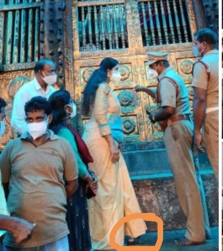 கோயில் முன்பு நிற்கும் விஜயதரணியின் காலில் செருப்பு இருப்பதாக வட்டமிட்டு வலைத்தளங்களில் பகிரப்படும் புகைப்படம்.