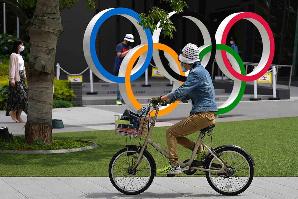 A woman rides a bicycle near the Olympic Rings
