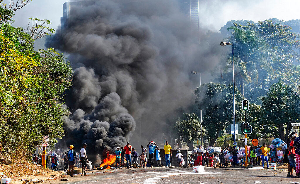 Looters outside a shopping centre alongside a burning barricade in Durban, South Africa