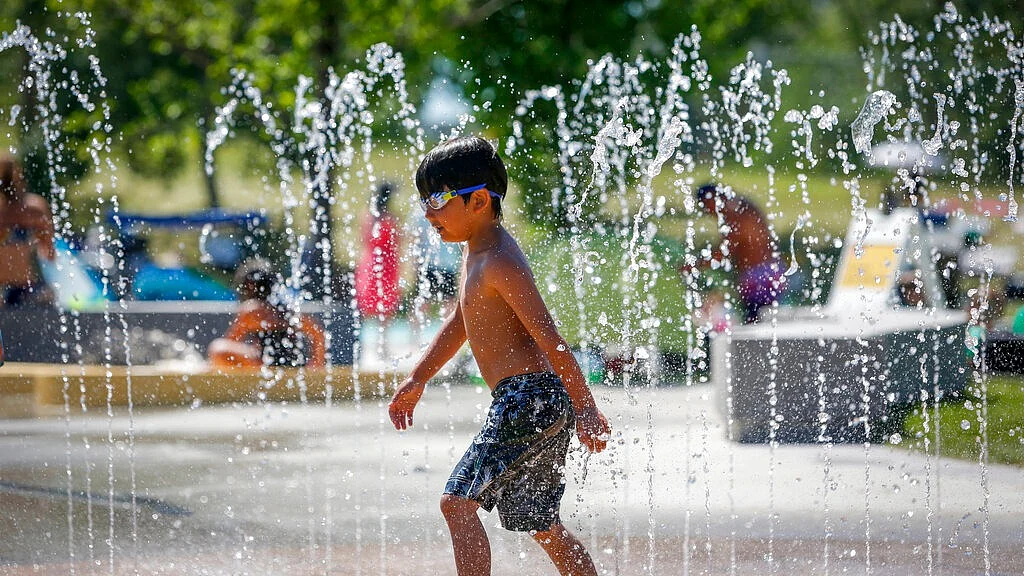 A young boy runs through a fountain
