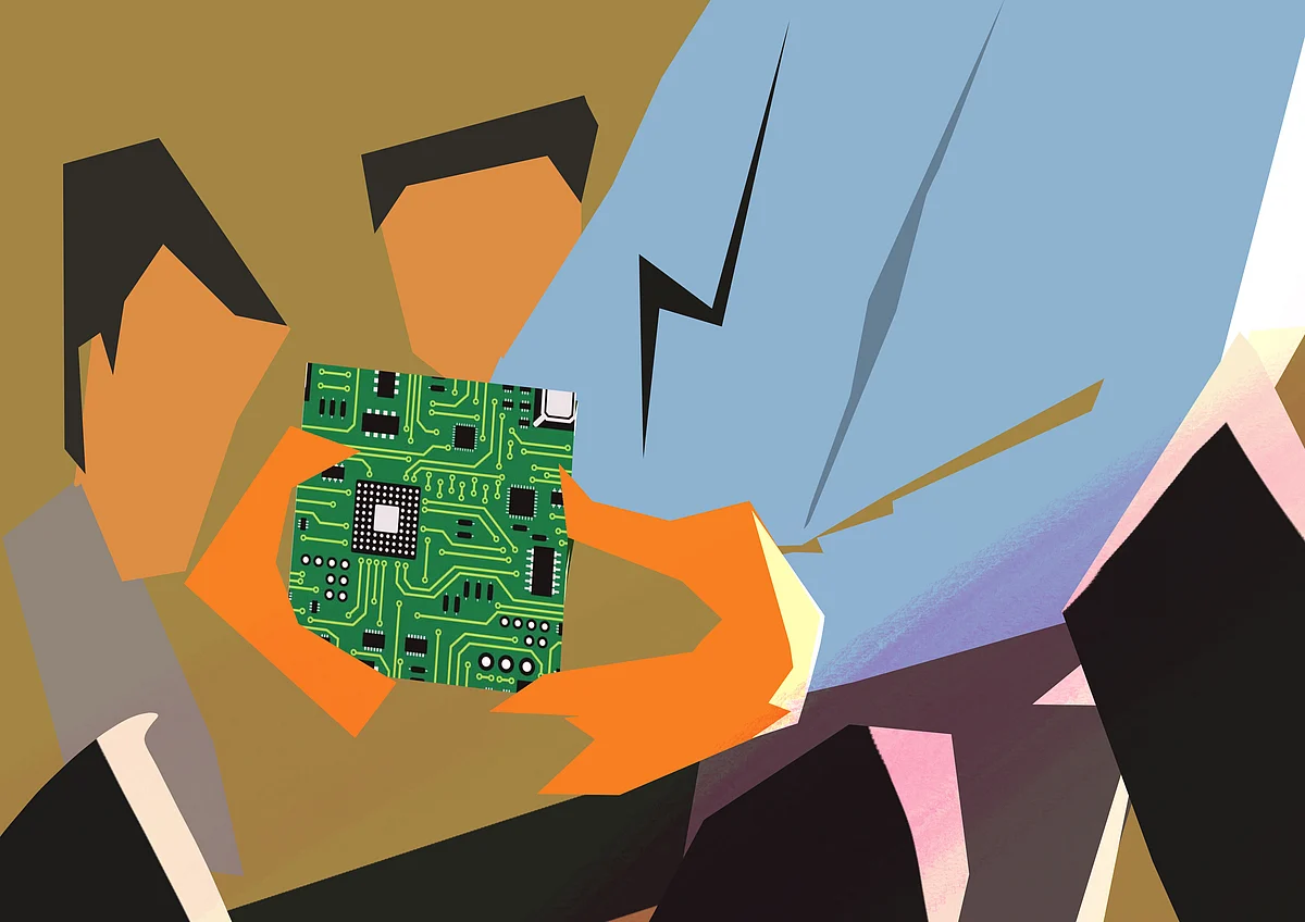 Bharath holding an electronics circuit board in his hand in front of his team