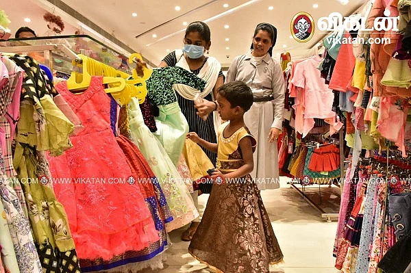 துணிக்கடையில் உடை தேர்வு செய்யும் சிறுமி