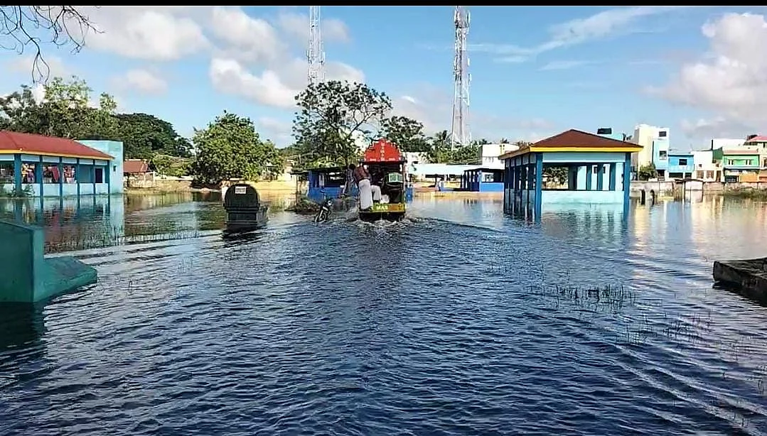 சூழ்ந்துள்ள மழைநீரில் செல்லும் அமரர் ஊர்தி